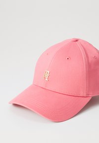 Gorra de algodón rosa con visera curvada, logo bordado en dorado y seis agujeros de ventilación en la corona para transpirabilidad.