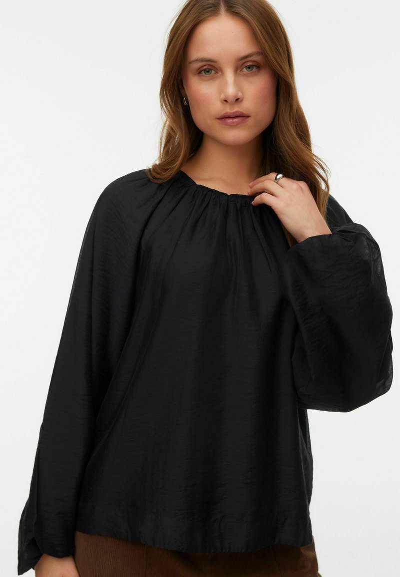 Blusa nera a maniche lunghe con scollatura arricciata e maniche voluminose, realizzata in un tessuto testurizzato e dal fit morbido.