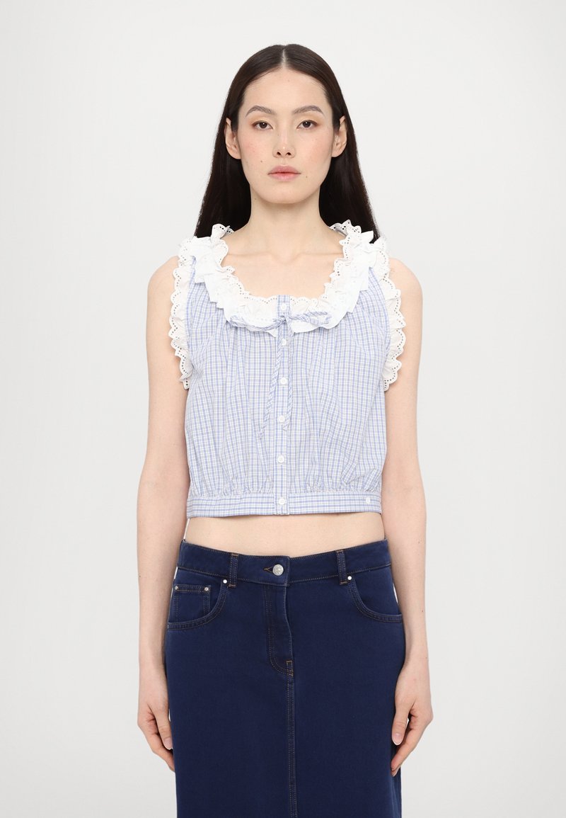Blauw-witte geruiten cropped top met een ruffelnek in het wit, knoopsluiting en elastische tailleband, gecombineerd met een donkerdenim rok.