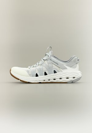 Chaussure de sport légère en blanc et gris avec une tige en mesh respirant, des sangles élastiques, et une semelle en caoutchouc blanche texturée avec des accents noirs.