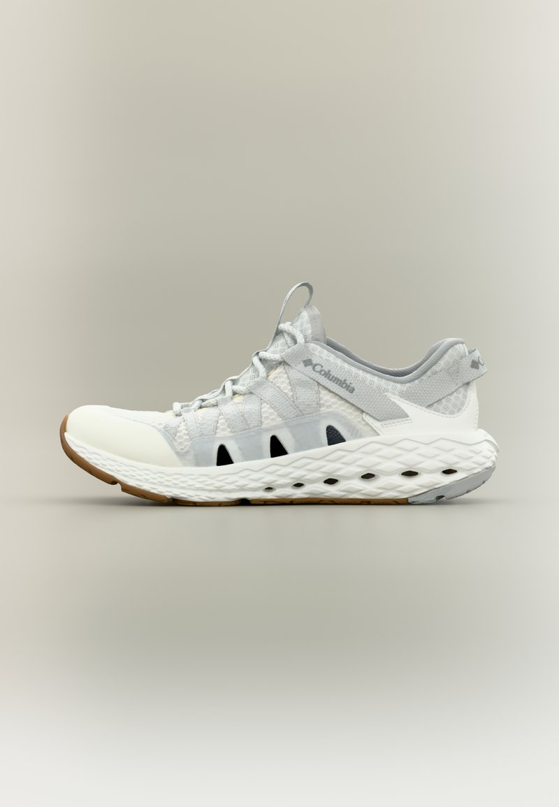 Ελαφρύ αθλητικό παπούτσι σε λευκό και γκρι με επάνω μέρος από διαπνέον διχτυωτό υλικό, ελαστικούς ιμάντες και υφήσει σόλα από λευκό καουτσούκ με μαύρες λεπτομέρειες.