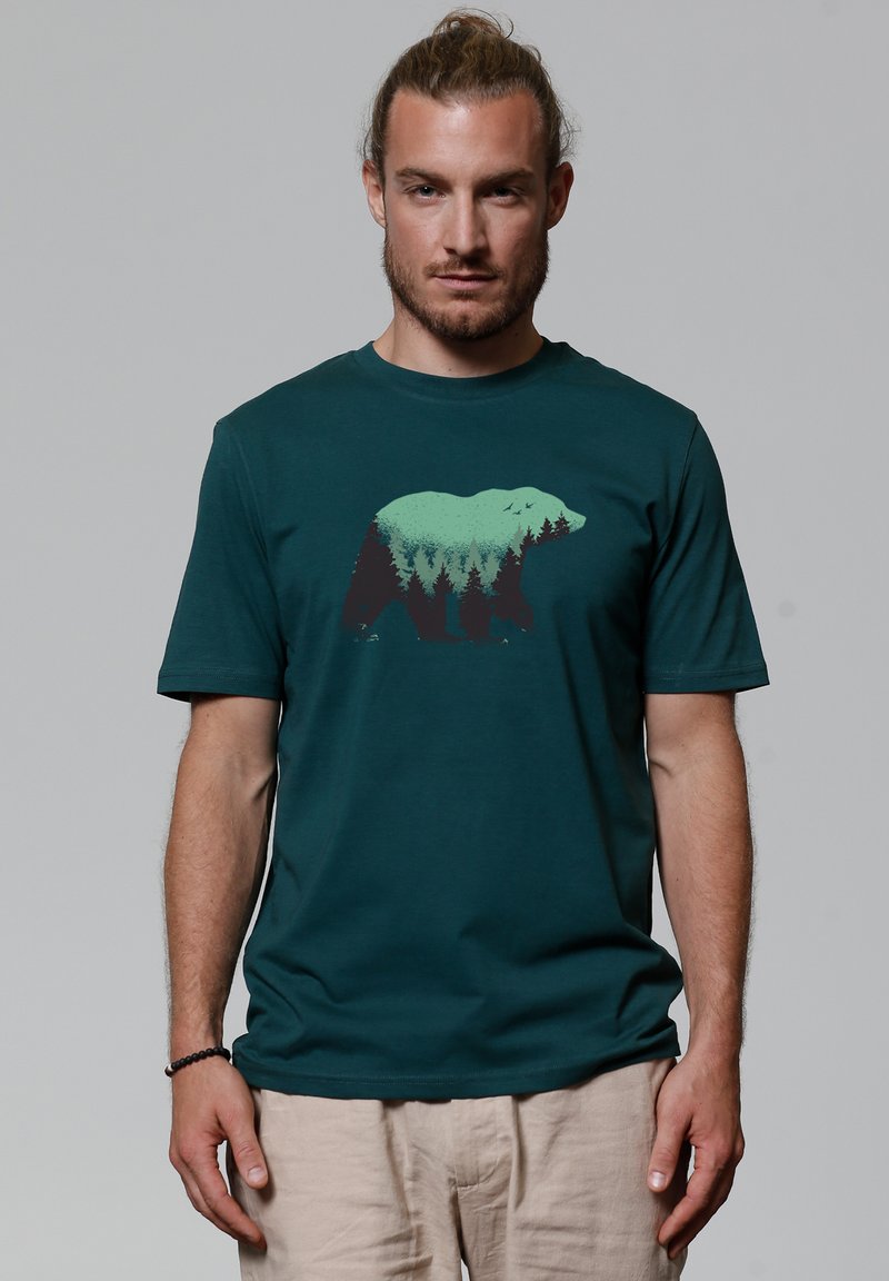 Teal katoen t-shirt met een silhouet van een beer en een bosontwerp in groen en zwart. Ronde halslijn en korte mouwen.