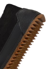 Baskets montantes noires avec une tige en textile texturé, semelle en caoutchouc à bords dentelés et accents en cuir lisse pour plus de durabilité.