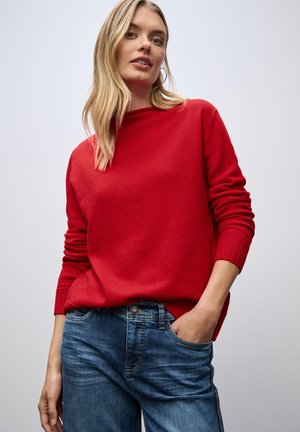 Rode pullover met een geribbelde halslijn en mouwen, gemaakt van zacht materiaal. Gecombineerd met blauwe jeans met een klassieke 5-pocket ontwerp.