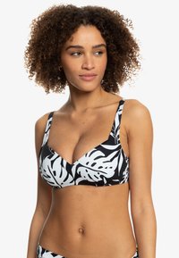 Black and white bikini top with a leaf pattern, featuring wide straps and a v-neck design, made from stretchy material.