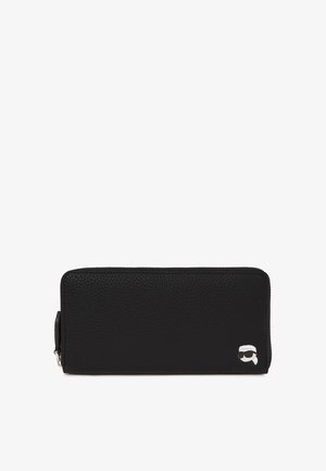 Carteira de couro preto com uma superfície texturizada, fecho de zip e um detalhe em prata no logótipo na frente. Forma retangular, design elegante.