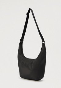 Sort nylon skulderveske med en buet form, justerbar rem og glidelås på toppen. Glatt tekstur, minimalistisk design og uten synlige metallbeslag.