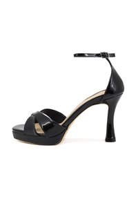 Sandal con tacco alto in vernice nera, dotata di plateau, cinturino alla caviglia e design con incrocio sulla parte superiore. Texture liscia e finitura lucida.