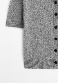 Cardigan grigio con maniche corte, realizzato in tessuto di maglia testurizzata, con orlo a coste e bottoni neri lungo la parte anteriore.