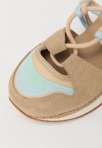 Scarpa in suede beige con design a strati multicolore in azzurro chiaro, verde menta e beige, suola piatta e chiusura con lacci.
