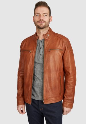 Chaqueta de cuero marrón con un collar alzado, dos bolsillos con cremallera y una textura suave, usada sobre una camiseta henley gris.