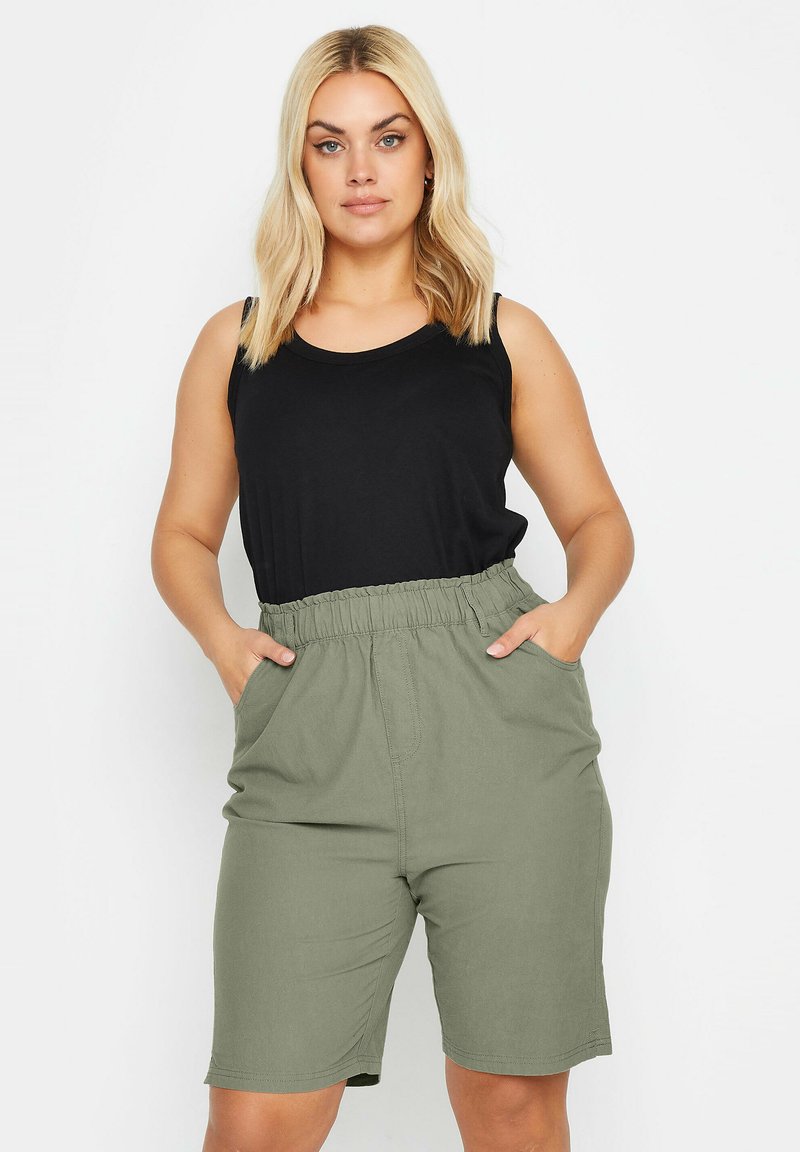 Haut sans manches noir associé à un short olive vert, de longueur genou, avec une taille élastique et deux poches latérales. Texture de tissu lisse.