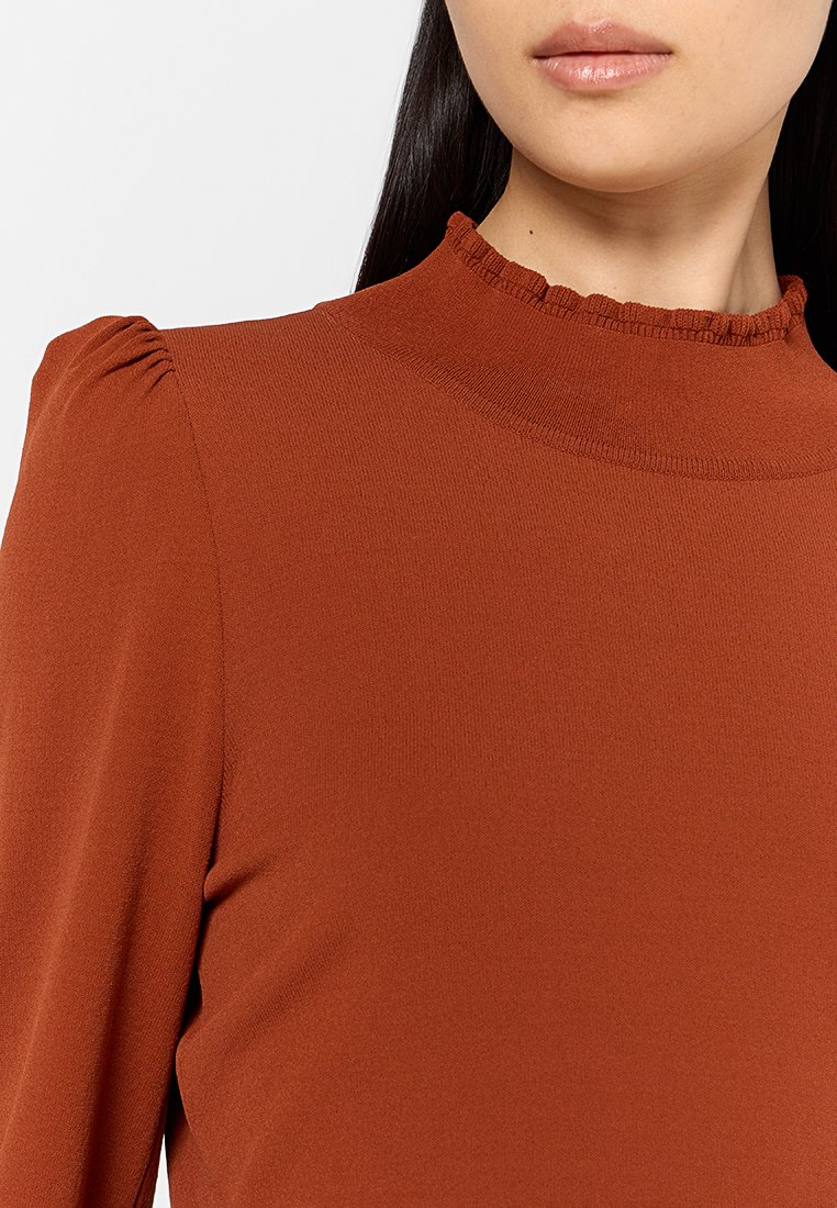 Rostfarbene Bluse mit hohem, gerafftem Kragen; verfügt über kleine Falten an den Schultern und eine glatte, eng anliegende Textur.