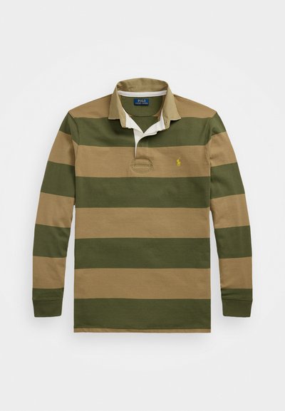 Ilgi piedurkņu regbija krekls ar mainīgiem zaļiem un brūniem svītrām, ribota apkakle un neliels izšūts logs virs kreisā krūšu lāpstiņa.