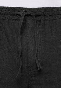 Zwarte linnen shorts met een elastische tailleband, voorzien van een trekkoord voor aanpassing en een gladde textuur. Minimalistisch ontwerp zonder patronen.