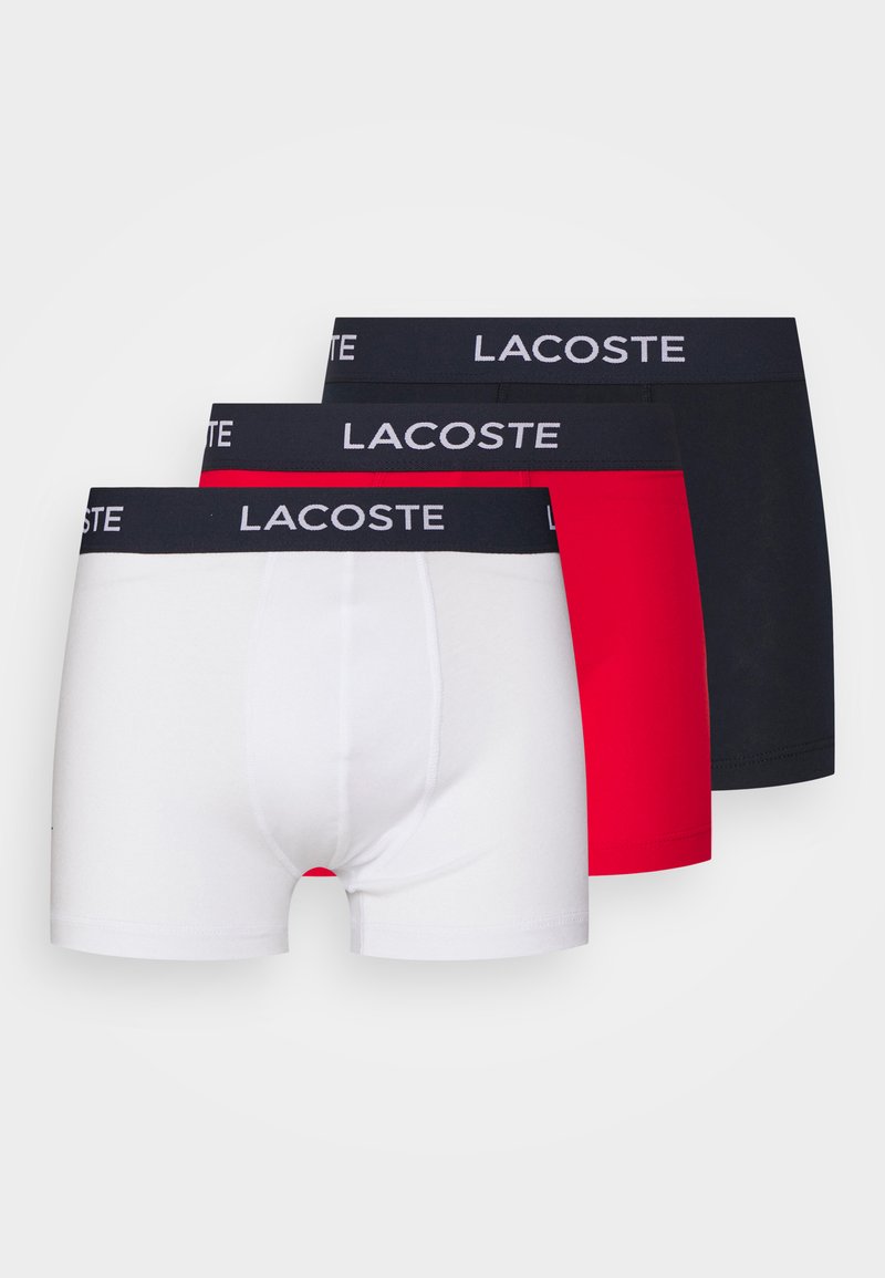 Conjunto de três boxers em branco, vermelho e preto. Tecido macio em mistura de algodão com cinturas elásticas apresentando o logótipo "LACOSTE" em branco.