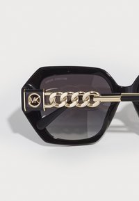 Ochelari de soare negri, supradimensionați, cu ramă hexagonală, lentile degradate, embellisment din lanț auriu și detaliu cu logo pe tempă.