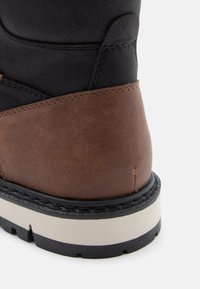 Ruske nahkaste gležnjarje z črnim zgornjim delom, s kontrastnim šivanjem in debelim belim ter črnim podplatom.