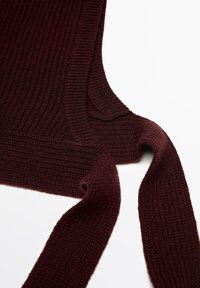 Dark burgundy knitted sleeveless garment with a wide ribbed texture and long knitted ties on a white background.