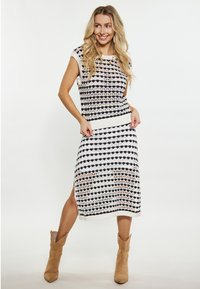Abito lavorato a maglia con motivo a righe in nero, bianco e pesca, con maniche corte e silhouette aderente. Stivaletti color cammello completano l'outfit.