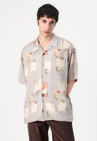Camasa cu maneci scurte de culoare gri deschis, cu imprimeuri colorate florale și animale, având un guler cu butoni și un buzunar pe piept. Material moale, croi lejer.