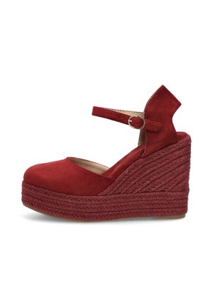 Zapato de tacón cuña de ante rojo con suela plataforma trenzada y correa ajustable en el tobillo con una hebilla redonda de metal.