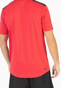 Rode sportieve T-shirt met korte mouwen, gladde textuur en een ronde zoom. Zwarte accenten op de schouders, aansluitend ontwerp.