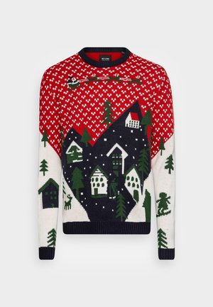 Pull de Noël rouge, blanc et marine avec des motifs de village enneigé, arbres, Père Noël en traîneau, rennes et skieur.