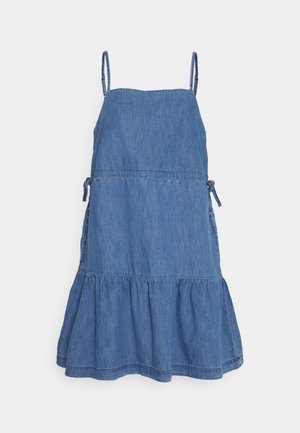 Robe sans manches en denim bleu avec bretelles fines réglables, liens à la taille et ourlet à volants sur fond blanc.