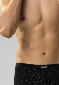 Czarne bokserki z zielonym wzorem liści; miękka tkanina, elastyczny pas z metką "ATLANTIC"; gładka faktura, dopasowany krój.