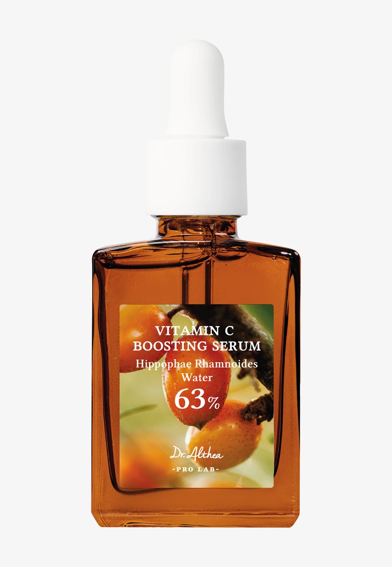 Brun glass dropperflaske med hvit kapsel. Etikett med grønn og oransje design, teksten leser "Vitamin C Boosting Serum" og ingredienser.