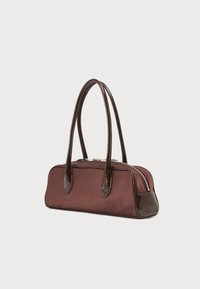 Καφέ ορθογώνια τσάντα χειρός με σκούρα καφέ μακριές λαβές, ασημένιο φερμουάρ και δερμάτινες γωνιακές λεπτομέρειες πάνω σε λευκό φόντο.