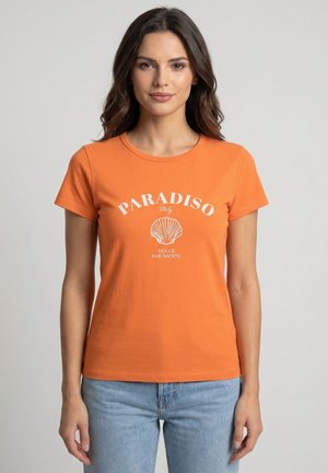 Donna con capelli scuri che indossa una maglietta arancione con una grafica di conchiglia bianca e la scritta "PARADISO Italy Dolce Far Niente", abbinata a jeans azzurri.