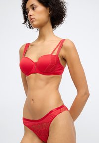 Set de lenjerie roșie, ce include un sutien cu padding, cu accente din dantelă și bretele subțiri ajustabile, însoțit de un chiloțel asortat, cu dantelă.