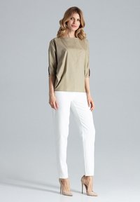 Beżowa bluzka z krótkim rękawem, szerokim dekoltem i bocznymi rozcięciami, zestawiona z dopasowanymi białymi spodniami i beżowymi szpilkami. Gładka tekstura materiału.