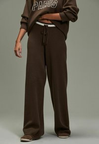 Br�ązowy dzianinowy sweatshirt z napisem "PARIS" i dopasowanymi spodniami typu wide-leg. Elastyczny pas ze sznurkiem. Teksturowana, miękka tkanina.