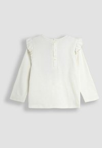 Witte blouse met lange mouwen en ruffles op de mouwen, ronde hals en knoopsluiting op de rug. Zachte stof met een gladde textuur.