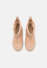 Beige gevoerde enkellaarsjes met een gladde textuur, voorzien van een trekband, elastisch koord en een contrasterend zoolontwerp.