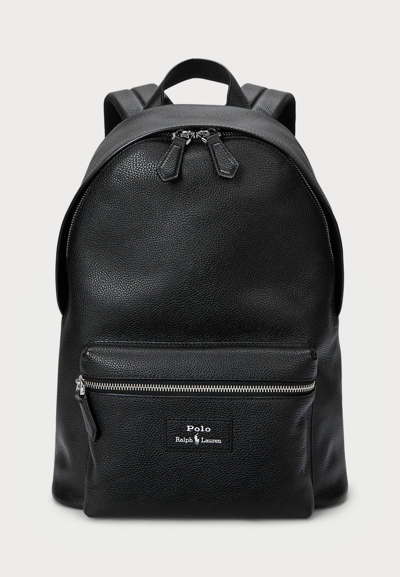 Black leather backpack with a textured finish, round shape, top zipper, front zippered pocket, and a logo patch. Dual adjustable straps.