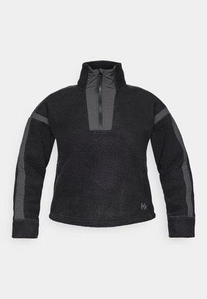 Crni flis pulover s visokim ovratnikom, četvrtastim zatvaranjem i sivim akcentima na rukavima. Mekana tekstura s opuštenim krojem.