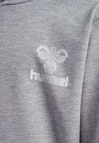 Grijze sweatshirt met een gladde textuur, voorzien van een wit logo van een gestileerde bij en het woord "hummel" in een vet lettertype.