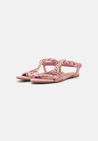 Pink braided sandals with flat soles, T-strap design, and gold-tone beads. Made of synthetic material with a smooth texture.