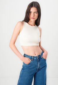 Cream ribbed crop top with a round neckline, paired with high-waisted blue denim jeans featuring a classic five-pocket design.