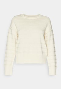 Suéter de color crema con cuello redondo de canalé, mangas largas y rayas horizontales texturizadas. El material parece suave y tiene un corte holgado.