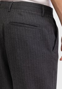 Halli pinstripes püksid, mis on valmistatud tekstureeritud kangast. Omab tagataskut ja küljetaskuid, sobitunud lõikega ja siledate ääredega.