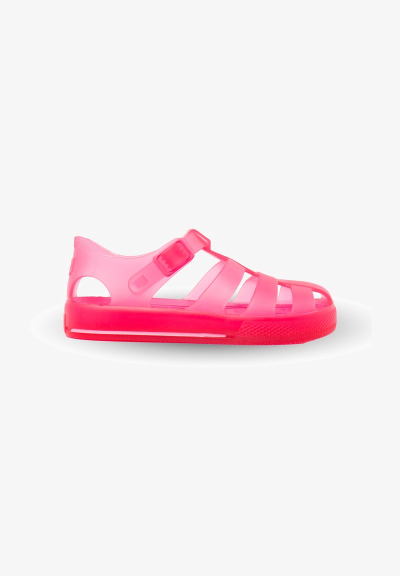 Pink transparent sandals with a rubber texture, featuring multiple side cutouts, two central straps, and an adjustable buckle closure.