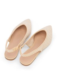 Beżowe płaskie buty typu slingback z ostrym noskiem, gładkim wnętrzem i subtelnym, textured paskiem. Prosty, minimalistyczny design.