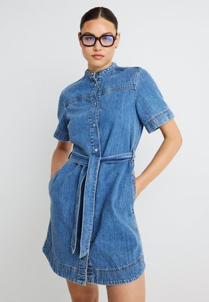 Vestido camisero de mezclilla con cuello con solapas, mangas cortas, cintura con cinturón y bolsillos laterales. Azul claro con detalles de costuras en contraste.