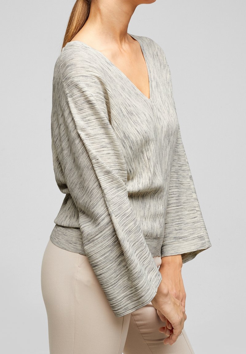 Light gray v-neck sweater with a textured pattern, wide sleeves, and a fitted waistband. Fabric appears soft and slightly stretchy.