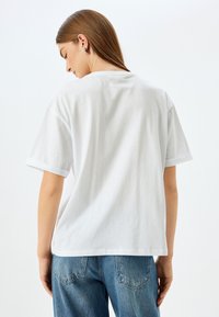 Witte katoenen t-shirt met een relaxte pasvorm, korte mouwen en een rechte zoom. De achterkant is eenvoudig zonder enige graphics of patronen.